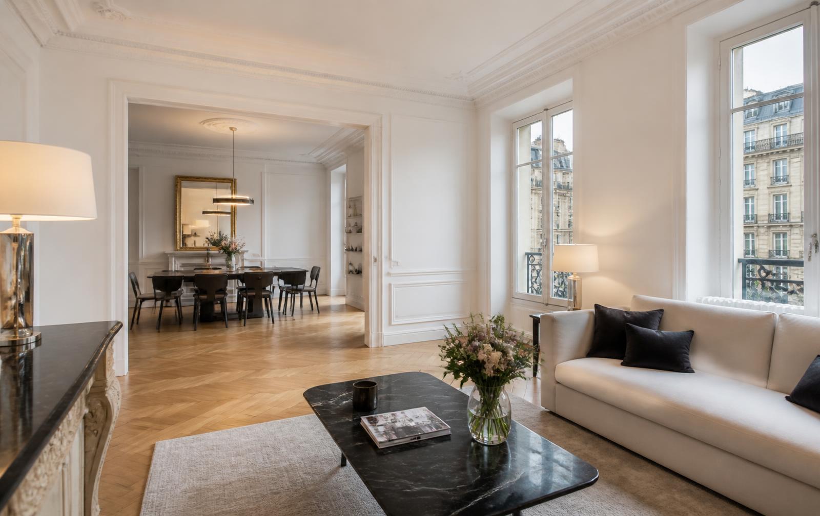 Salon parisien avec parquet à chevrons, moulures et grandes fenêtres